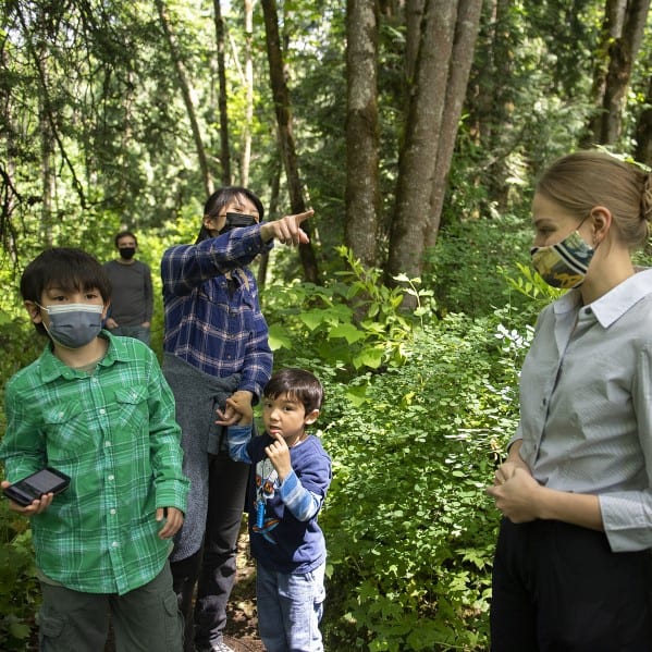 Tomoko O'Rourke points the way while navigating Columbia Springs with her sons Tyler, 10, and Eric, 5, with her husband, Quinn, bringing up the rear. With them is Columbia Springs outreach specialist Kylie Sahota, right, who wrote the material for a new Geocaching Adventure Lab tour of the site. (Amanda Cowan/The Columbian)